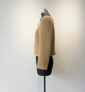 Gedetailleerd zij-aanzicht van een chic beige wollen tweed kort jasje met gouden knopen.