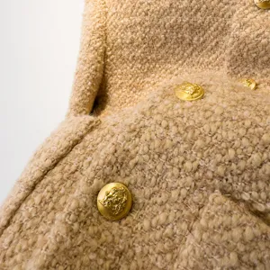 Tweed jas stof detail, premium wolmix textuur, elegante gouden wapenknop close-up weergave stuk.