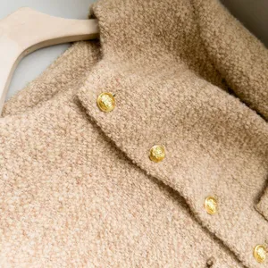 Getextureerde tweed jas detail, klassiek rond halsdesign met vintage gouden knopen.