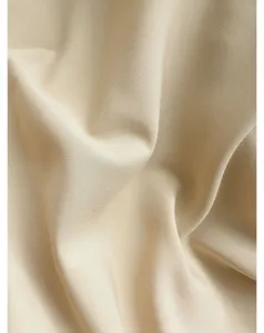 Beige stof detail textuur close-up, zacht gedrapeerd glad textiel materiaal.