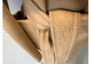 Camel cashmere wool blend wrap coat detail showing luxurious water ripple texture and belt.