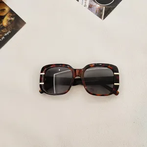 Square tortoise sunglasses detail shot with gold metal accents and UV protection lenses.