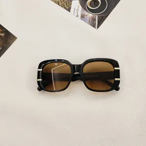 Close-up of stylish square sunglasses featuring black thick frames and brown gradient lenses.