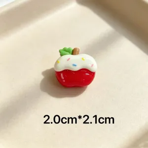 Cute red apple resin charm with white icing and colorful sprinkles, detailed close-up shot.