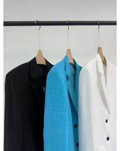 Detailopname van lichte zomerse damesblazers hangend aan een kledingrek met fijne textuur.