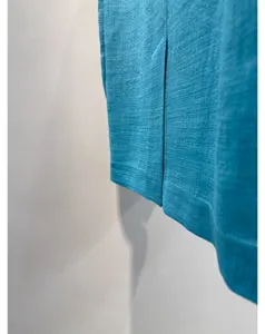 Detailopname van turquoise triacetaatstof met fijne geweven textuur en zoom van het pak.
