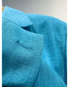 Blauwe blazer stof detailfoto, dames zomer dunne pak jasje revers textuur close-up.