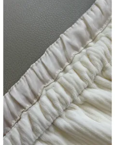 Close-up detail shot of white corduroy pants waistband, soft texture and elastic drawstring.