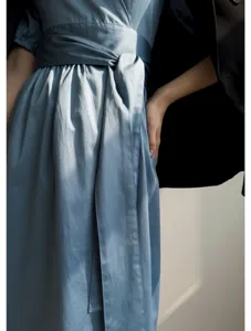 Détail de robe portefeuille bleu clair gros plan avec manches et ceinture design élégant.