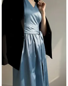 Détail de la robe midi en satin bleu clair au design élégant avec un blazer noir.