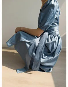 Vue détaillée de l'élégante robe bleue à manches bouffantes avec tissu doux et ceinture.