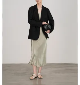 Gedetailleerd overzicht van de elegante satijnen jurk gecombineerd met een chique zwarte blazer.