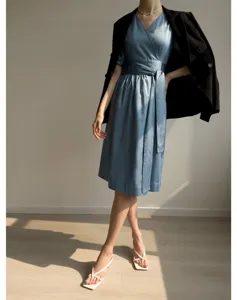Détail de robe midi portefeuille bleue élégante avec col V, manches courtes et nouage.