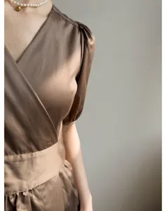 Détail de robe style français col V manches bouffantes, texture tissu brillant.