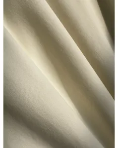 Close-up detail shot of soft cotton poplin fabric with elegant draping texture and fine weave.