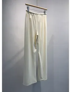 Casual off-white pleated wide-leg pants detail, showing elastic waistband and draping fabric.