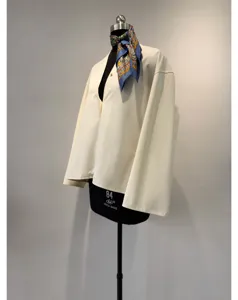 Detail view of the cream cotton wide-sleeve blouse with V-neck and unique mandarin collar.