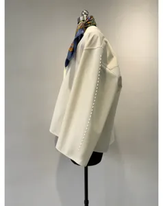 Close-up detail of off-white cotton loose long-sleeve blouse sleeve with stylish scarf collar.