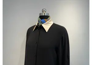 Detailed view of the black long-sleeve blouse featuring a contrasting cream collar and silk scarf.