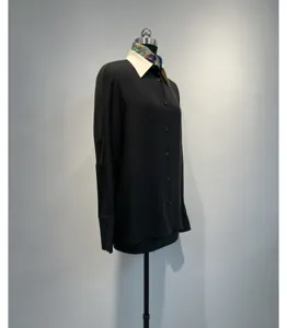 Detailed view of a black long sleeve shirt featuring a contrasting light collar and floral silk scarf.