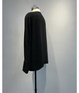 Detail view of a stylish black long-sleeve blouse featuring a contrast cream collar and design.