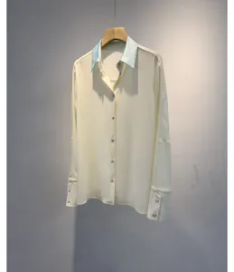Detailed view of elegant off-white long sleeve shirt with contrast light blue lapel button down.