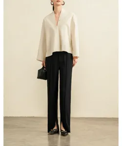 Detail shot of women's chic white V-neck blouse, wide sleeves, refined fabric and minimalist style.