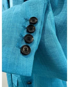 Detailopname van de blauwe damesblazermanchet met vier knopen, hoogwaardige stoftextuur.