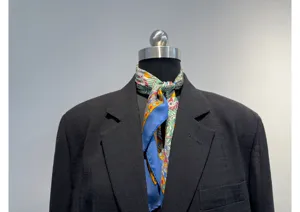 Close-up detail van zwarte damesblazer kraag gecombineerd met een kleurrijke zijden sjaal.