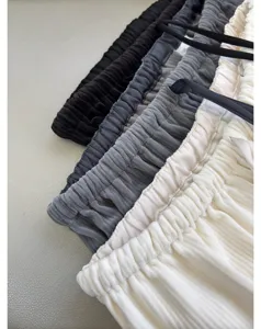 Close-up detail of soft corduroy trousers waistband, casual stacked pleated pants design.