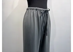 Detailed view of dark grey pleated wide-leg pants with elastic drawstring waist.