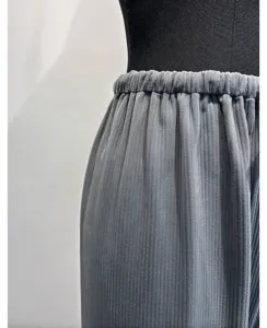Detail shot of grey elastic waist pleated trousers, showing soft corduroy fabric texture.