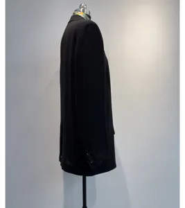 Zijdelingse detailweergave van een zwarte lichte damesblazer met knopen op de mouw.