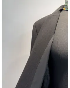 Detailopname van een zwarte damesblazer met fijne snit en hoogwaardige stofstructuur.