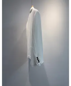 Detail van een lichte witte zomerblazer, ademende stof met zwarte manchetknoppen.