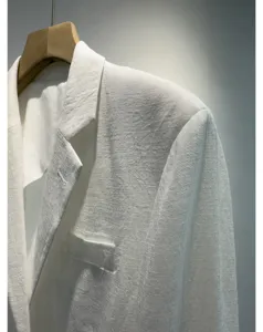 Gedetailleerd uitzicht op een lichte witte dames zomerblazer hangend aan een kledinghanger.