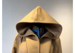 Camel hooded woolen coat detail showcasing soft fabric texture and matching blue scarf.