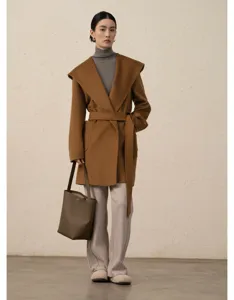 Detailed view of the stylish hooded wool wrap coat in camel, paired with elegant leather bag.