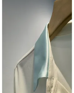 Close-up detail view of contrasting satin collar shirt hanging on wooden hanger, smooth texture.