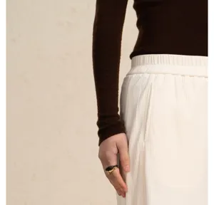 Detailed view of white corduroy trousers fabric texture and elastic waistband with slim fit.