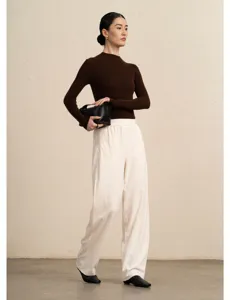 Detail view of women brown knit sweater and white corduroy wide-leg pants outfit in studio.