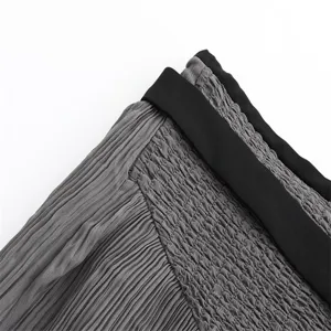 Close-up detail shot of the high-waist pleated midi skirt waistline with contrast band.