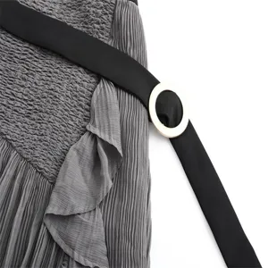 Grey pleated high-waist skirt detail showing smocked waist, ruffles, and chic black belt.