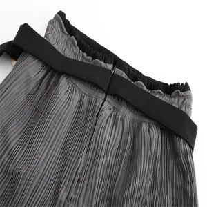 Detail view of women high waist grey pleated skirt with black wide belt and ruffles.