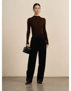 Detailed shot of woman wearing elegant brown knit sweater and black corduroy trousers.
