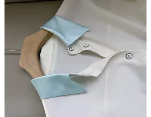 Detail shot of a white blouse featuring a contrasting light blue satin collar and buttons.
