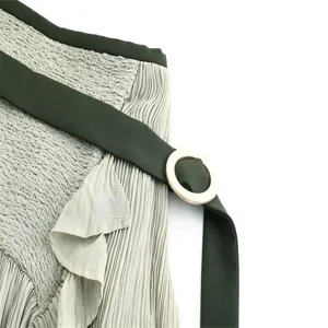 Detail shot of the pleated midi skirt showing smocked waist, ruffles, and dark green belt buckle.