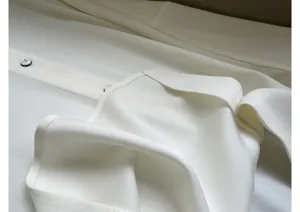 High quality silk-like white blouse fabric detail with delicate buttons and elegant collar.