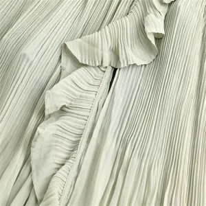 Detailed close-up of light green pleated fabric featuring delicate ruffles and fine texture.