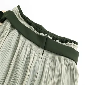 Detailed view of women high waist pleated midi skirt with contrast dark green waistband.